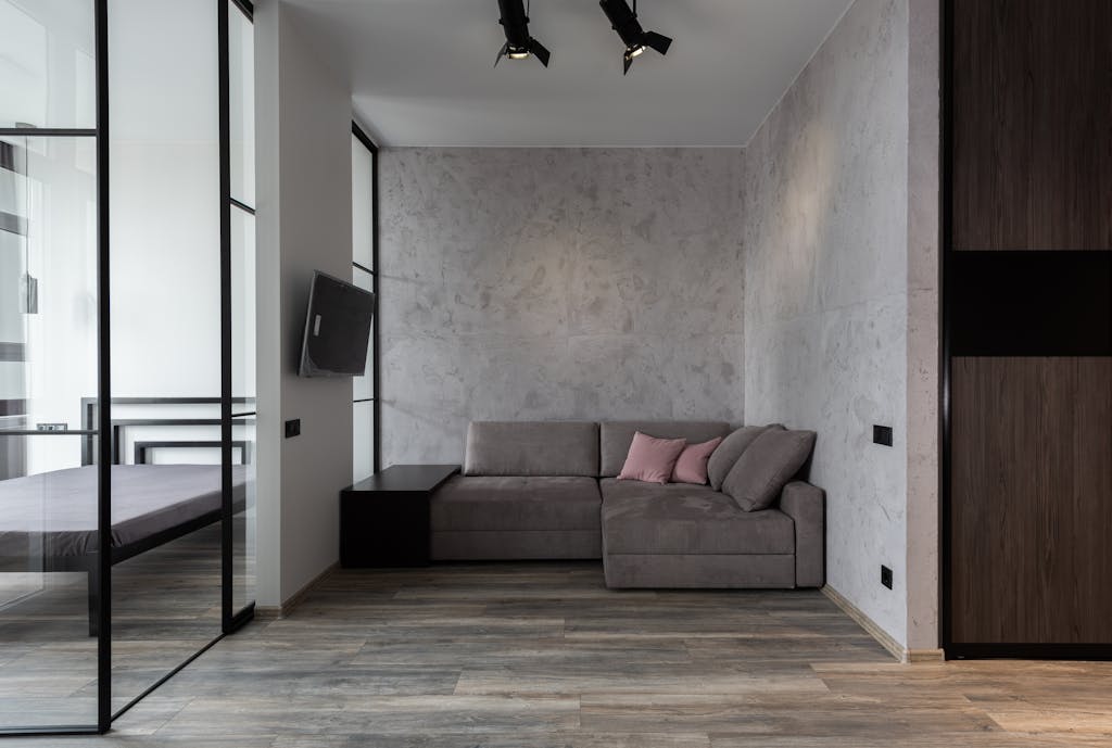 A contemporary living room with a minimalist sofa and glass wall setup.