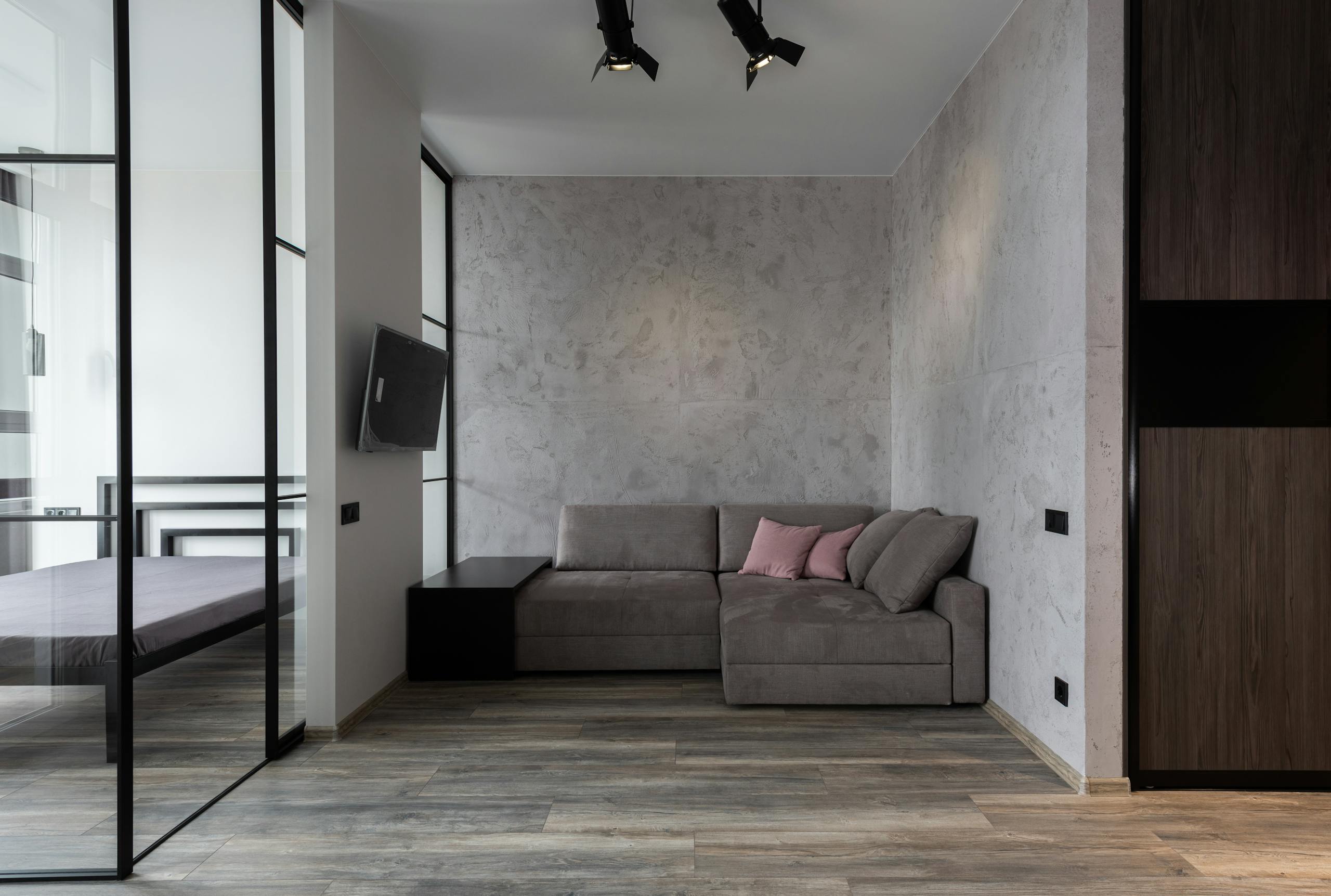 A contemporary living room with a minimalist sofa and glass wall setup.