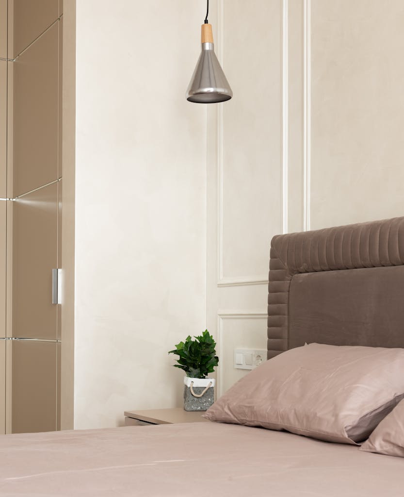 Modern minimalist bedroom featuring soft beige tones, a plush headboard, and elegant lighting for a cozy atmosphere.