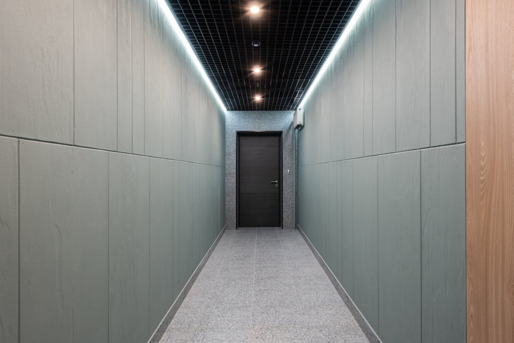 Sleek modern corridor with soft lighting and minimal design leads to a closed doorway.